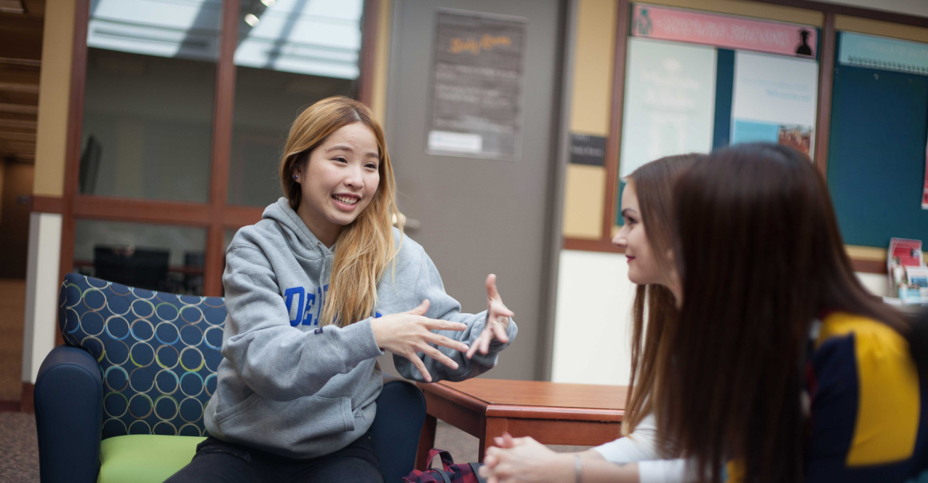 A happy young woman talks with friends on campus. 