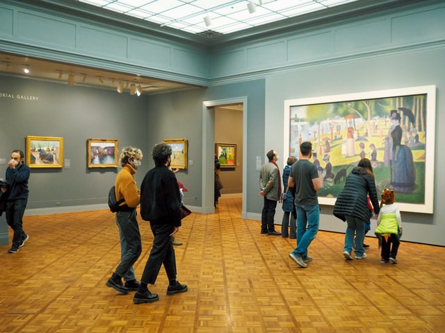 Visitors at an art museum observe a large painting
