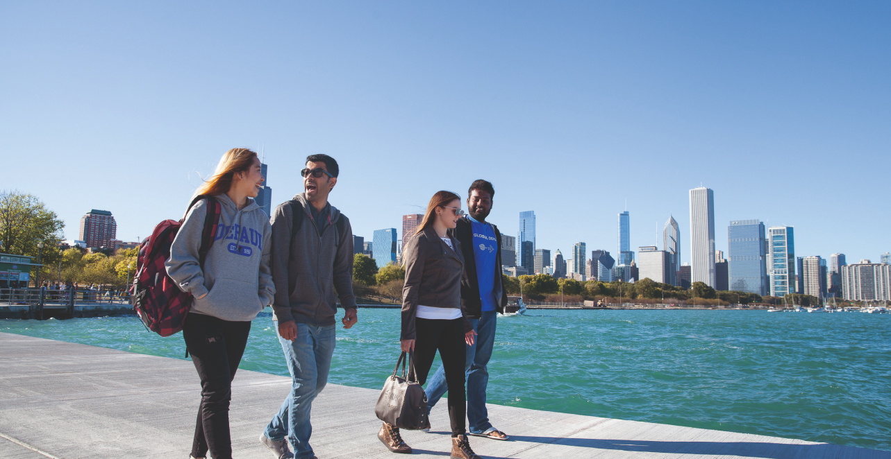 Four DePaul students walk along the waterfront of Chicago