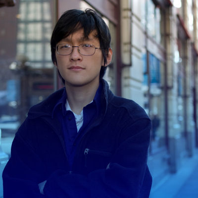 A pensive looking young man in glasses in the city